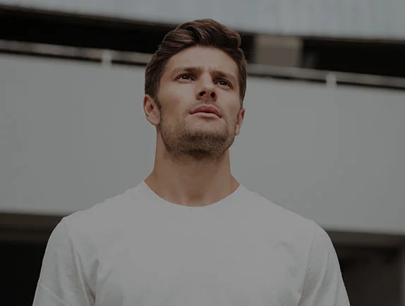 A man in a white t-shirt looking directly above the camera.